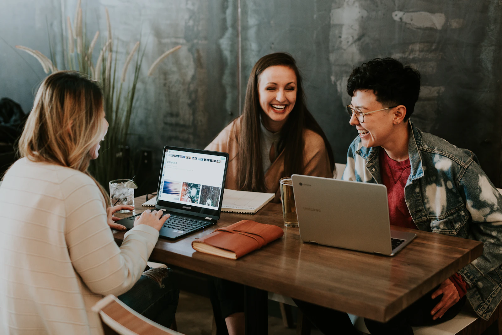 Three people sharing ideas and laughing around a table